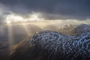 Sun breaking through cloud over snowy mountains near Glenfinnan; Scotland, United Kingdom Sun breaking through cloud over snowy mountains near Glenfinnan; Scotland, United Kingdom