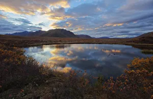 Sunset clouds reflected in a small pond in the peel watershed along the dempster highway; Yukon canada Sunset clouds reflected in a small pond in the peel watershed along the dempster highway; Yukon canada