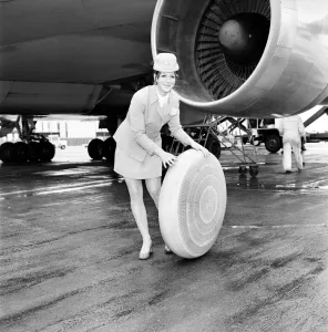 Air hostess sitting by a plane rolling a wheel along. A 2 *** Local Caption Air hostess sitting by a plane rolling a wheel along. A 2 *** Local Caption