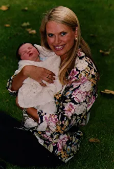 Anneka Rice holding baby smiling sitting on grass wearing flowery print shirt TV Anneka Rice holding baby smiling sitting on grass wearing flowery print shirt TV