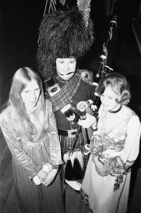 Two ball goers pose with the piper at the Birmingham and West Midlands Scottish Society Two ball goers pose with the piper at the Birmingham and West Midlands Scottish Society