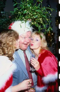 Benny Hill comedian December 1991 Being kissed under mistletoe by two girls Benny Hill comedian December 1991 Being kissed under mistletoe by two girls
