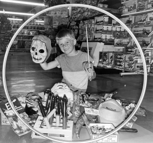 A boy surrounded by toys in a toy shop. July 1984 A boy surrounded by toys in a toy shop. July 1984