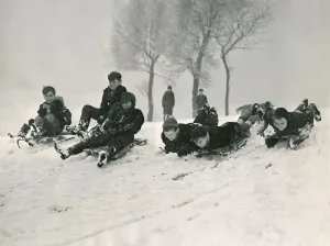 Children sledging down a hill in snow smiling and laughing after a havy snowfall Children sledging down a hill in snow smiling and laughing after a havy snowfall