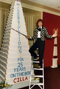 Cilla Black on a step ladder about to cut her cake with a sword celebrating her 25 Cilla Black on a step ladder about to cut her cake with a sword celebrating her 25