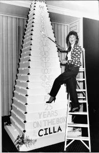 Cilla Black TV Personality climbs a ladder with a sward to cut the huge party cake in Cilla Black TV Personality climbs a ladder with a sward to cut the huge party cake in