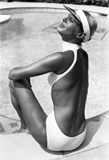 Clothing Beach. Tanned woman models sun visor and white one piece halterneck backless Clothing Beach. Tanned woman models sun visor and white one piece halterneck backless