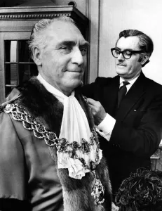 Councillor James Eames being robed by his attendant Mr. Tom Freer before being elected Councillor James Eames being robed by his attendant Mr. Tom Freer before being elected