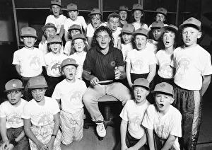 David Essex Singer surrounded by choir of school children wearing baseball caps David Essex Singer surrounded by choir of school children wearing baseball caps