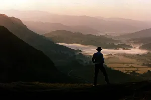 Dawn rises over the Lake District as a walker travels along a lakeland pass Dawn rises over the Lake District as a walker travels along a lakeland pass