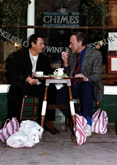 Don Henderson Actor & Michael Elphick actor sitting at pavement cafe table with shopping Don Henderson Actor & Michael Elphick actor sitting at pavement cafe table with shopping