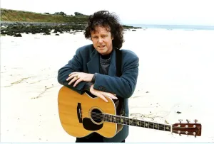 Donovan Pop Star of the 60s pictured at a beach with his guitar hanging around his neck Donovan Pop Star of the 60s pictured at a beach with his guitar hanging around his neck