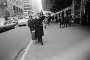 A doorman hailing a cab outside a Hotel. New York, 13th February 1981 A doorman hailing a cab outside a Hotel. New York, 13th February 1981