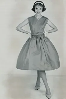 Fashion 1950s Model wearing a pinafore dress with a full skirt and white gloves Fashion 1950s Model wearing a pinafore dress with a full skirt and white gloves