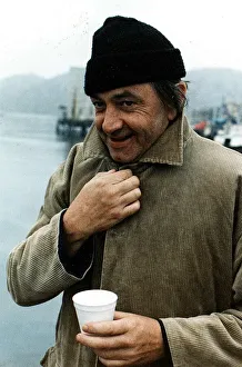 Bill Forsyth film director collar of coat turned up woollen hat paper cup on quayside Bill Forsyth film director collar of coat turned up woollen hat paper cup on quayside