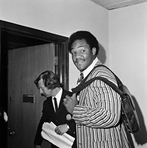 George Foreman at Heathrow airport, wearing a striped jacket and carrying a shoulder bag George Foreman at Heathrow airport, wearing a striped jacket and carrying a shoulder bag