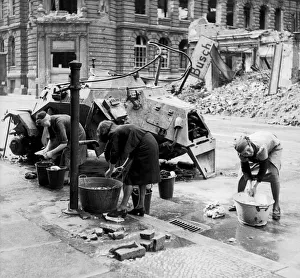 German women doing their washing in cold water in a street beside a knocked out German German women doing their washing in cold water in a street beside a knocked out German