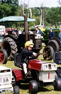 A little boy trying our a miniature tractor on show among the traction engines at A little boy trying our a miniature tractor on show among the traction engines at