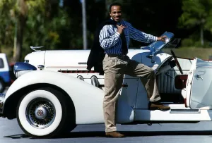 Lloyd Honeygham Boxer stands by a white classic car Lloyd Honeygham Boxer stands by a white classic car
