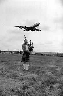 Lone bagpipe player Jim Thomas playing as a jumbo jet flies overhead May 1975 Lone bagpipe player Jim Thomas playing as a jumbo jet flies overhead May 1975