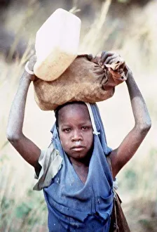 Mali Dogon Tribe a young girl carrying heavy item on her head Mali Dogon Tribe a young girl carrying heavy item on her head