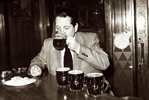 Man in pub drinking several pints of beer which are lined up on the bar ready Man in pub drinking several pints of beer which are lined up on the bar ready