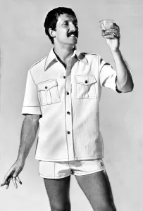 A man wearing a shirt with shorts looking at a glass of whisky A man wearing a shirt with shorts looking at a glass of whisky