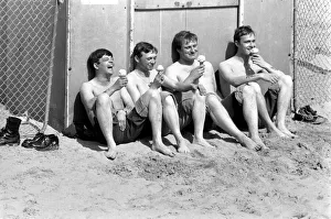 Four men sitting enjoying an ice cream in the hot weather at Margate Beach Four men sitting enjoying an ice cream in the hot weather at Margate Beach