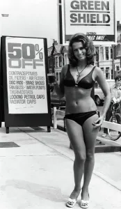 A 1972 print of a young woman in a bikini standing at a petrol pump