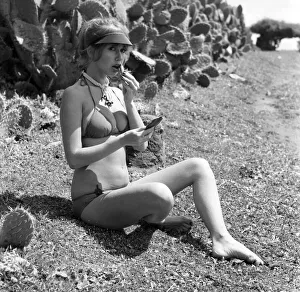 Model putting on her make up as she poses on a beach in Africa wearing a bikini Model putting on her make up as she poses on a beach in Africa wearing a bikini