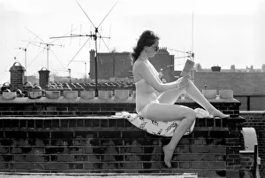 A model wearing a bikini reading a book as she sunbathes on a rooftop on Kings Road in A model wearing a bikini reading a book as she sunbathes on a rooftop on Kings Road in