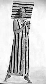 A model wearing six buttoned sleveless coat with a matching sun brim hat made in striped A model wearing six buttoned sleveless coat with a matching sun brim hat made in striped