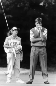 Nick Faldo Golf with caddy Fanny Sunesson holding the flag look on to the putting green Nick Faldo Golf with caddy Fanny Sunesson holding the flag look on to the putting green
