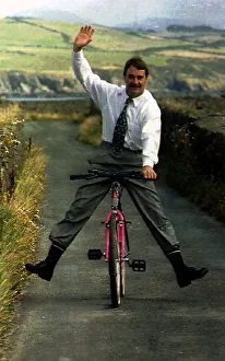 Nigel Mansell Formula One Racing Driver Riding A Bicycle Down A Country Lane Nigel Mansell Formula One Racing Driver Riding A Bicycle Down A Country Lane