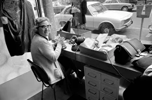 An old woman mending ladders in tights at a shop near the Champs Elysees in Paris An old woman mending ladders in tights at a shop near the Champs Elysees in Paris