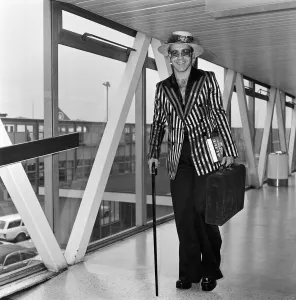Pop star Elton John wearing a hat trimmed with flowers and feathers Pop star Elton John wearing a hat trimmed with flowers and feathers