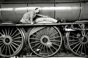 Railway worker cleans the sign on the wheels on the Flying Scotsman steam train Railway worker cleans the sign on the wheels on the Flying Scotsman steam train