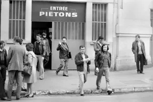 Renault factory workers leaving at the end of a shift through a door marked ' Renault factory workers leaving at the end of a shift through a door marked '