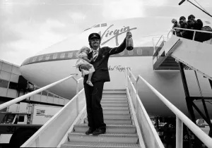 Richard Branson holding a bottle of champagne and his daughter on the steps of Richard Branson holding a bottle of champagne and his daughter on the steps of