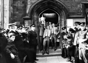 Ron Tatum carries the trophy as he and the members of the team leave the town hall Ron Tatum carries the trophy as he and the members of the team leave the town hall