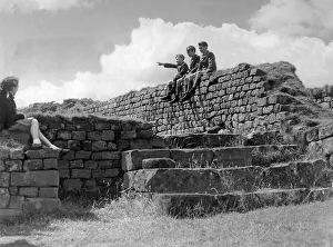Schoolchildren sitting on the wall of the Roman Granary at Housesteads Fort in Schoolchildren sitting on the wall of the Roman Granary at Housesteads Fort in