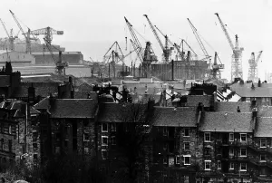Shipyard cranes rise above tenement apartment buildings by the River Clyde in Scotland Shipyard cranes rise above tenement apartment buildings by the River Clyde in Scotland