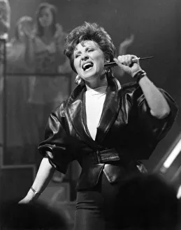 Singer Lulu dressed in leather jacket with microphone, on stage singing Singer Lulu dressed in leather jacket with microphone, on stage singing