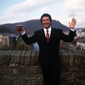 Tom Jones Singer in his home town in Wales standing by brick wall holding pint glass of Tom Jones Singer in his home town in Wales standing by brick wall holding pint glass of