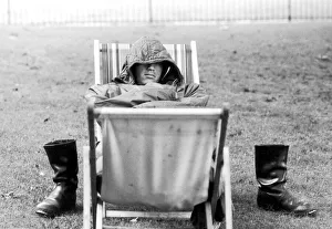 A weary traveller removes his boots as he takes a rest on a bed made from two deckchairs A weary traveller removes his boots as he takes a rest on a bed made from two deckchairs