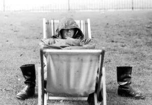 A weary traveller removes his boots as he takes a rest on a bed made from two deckchairs A weary traveller removes his boots as he takes a rest on a bed made from two deckchairs