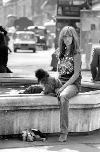 Woman stops at a fountain to rest her tired feet after walking her dog around the Kings Woman stops at a fountain to rest her tired feet after walking her dog around the Kings