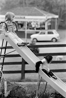 Three year old Emma Colbourne playing on the slide in her local park with a chimpanzee Three year old Emma Colbourne playing on the slide in her local park with a chimpanzee