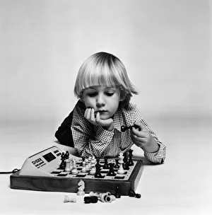 A young boy playing with 'Chess Challenger', an electronic chess game A young boy playing with 'Chess Challenger', an electronic chess game