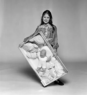 A young girl holding a doll and clothes toy set. December 1980 A young girl holding a doll and clothes toy set. December 1980